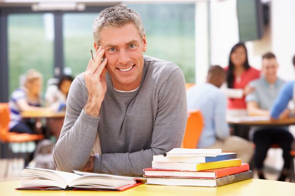 دانش آموز بالغ مرد در حال مطالعه در کلاس درس با کتاب
