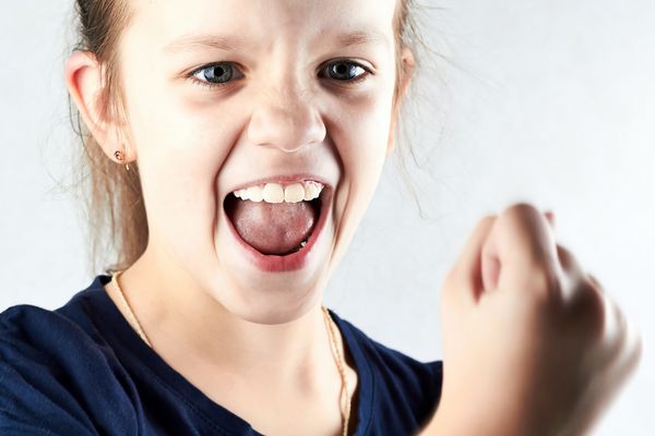 دختر عصبانی که جیغ می زند و مشت خود را نشان می دهد