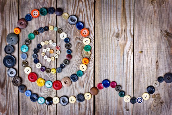 مجموعه ای از دکمه های قدیمی روی میز چوبی قدیمی