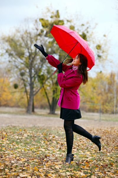 زن جوان زیبا با چتر در پارک پاییز