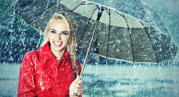 زنی زیبا که چتر را زیر باران نگه داشته است