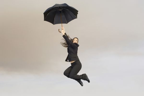 نمای کامل یک تاجر زن شاد با چتر در هوا