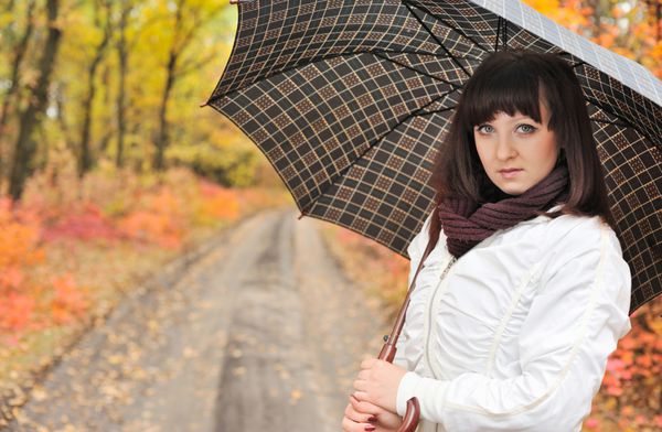 دختری در چوب پاییزی با چتر ظاهر اروپایی