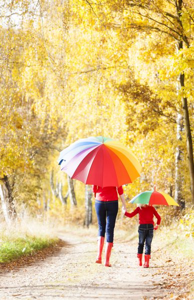 مادر با دخترش با چتر در کوچه پاییزی