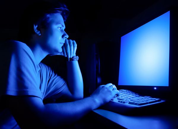 مرد مقابل صفحه کامپیوتر اتاق شب تاریک و نور آبی