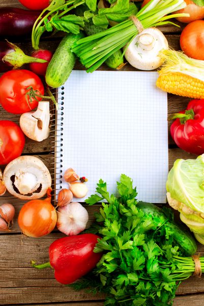 سبزیجات و ادویه های ارگانیک تازه روی پس زمینه چوبی و کاغذ برای یادداشت ها دفترچه یادداشت باز رژیم غذایی مفهوم رژیم غذایی