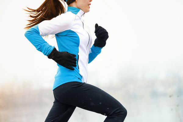 دویدن زن ورزشکار در حال دویدن در طول تمرینات زمستانی در بیرون در هوای سرد برفی از نزدیک سرعت و حرکت را نشان می دهد