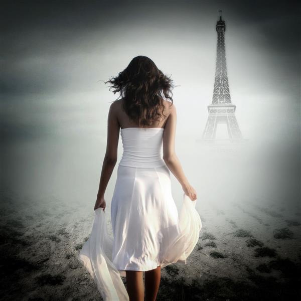 نمای عقب زن جوانی که در حال قدم زدن در مقابل برج ایفل در پاریس است