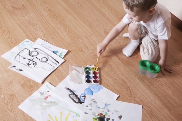 نمای مرتفع نقاشی پسر جوان با آبرنگ و قلم مو روی کف لمینت