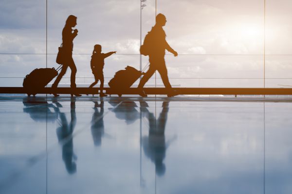 شبح خانواده جوان با چمدان در حال راه رفتن در فرودگاه دختری که چیزی را از پنجره نشان می دهد