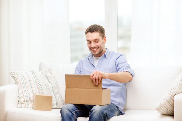 پست خانه و مفهوم سبک زندگی - مرد خندان با جعبه های مقوایی در خانه