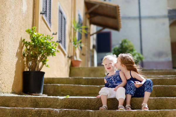دو خواهر کوچک زیبا روی پله‌های شهر ایتالیا نشسته‌اند