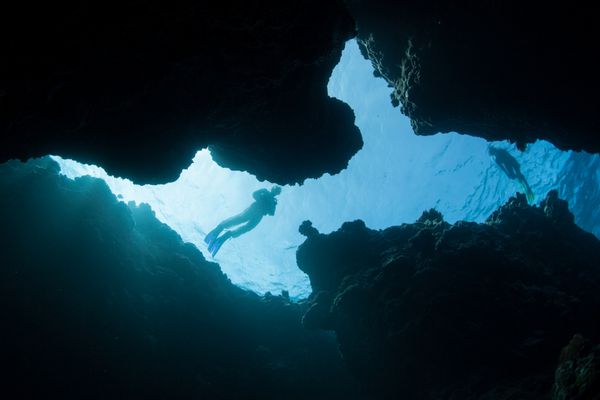 غواصی‌ها بر فراز شکاف تاریکی که به صخره‌های مرجانی در میکرونزی فرسایش یافته است حرکت می‌کنند این منطقه گرم و گرمسیری دارای صخره های زیبا و متنوع است