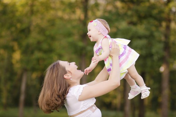 مادر در پارک با کودکش آن را پرت می کند بچه شاد میخنده