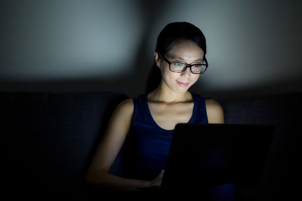 زن در شب از کامپیوتر لپ تاپ استفاده می کند