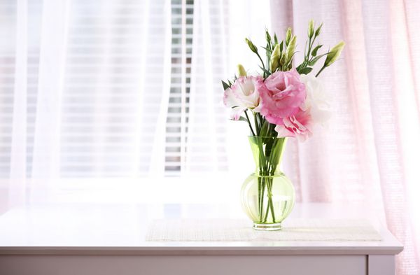 گل های زیبا در گلدان با نور از پنجره