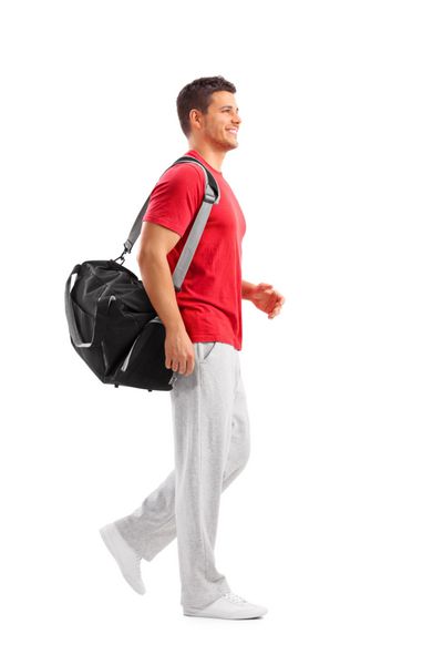 پرتره تمام قد از یک ورزشکار مرد که با یک کیف ورزشی جدا شده روی پس‌زمینه سفید راه می‌رود
