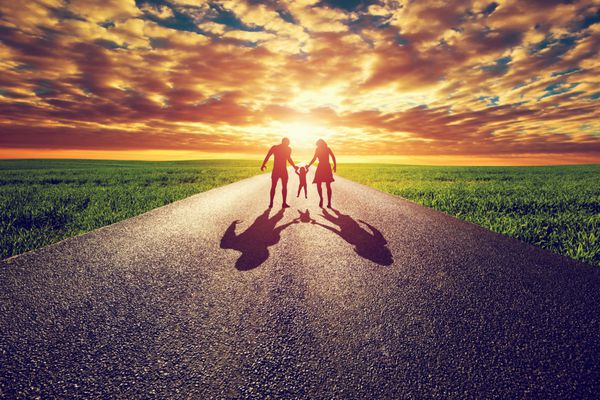 قدم زدن خانواده در جاده مستقیم طولانی راهی به سمت غروب خورشید مادر پدر و فرزند مفاهیم والدین
