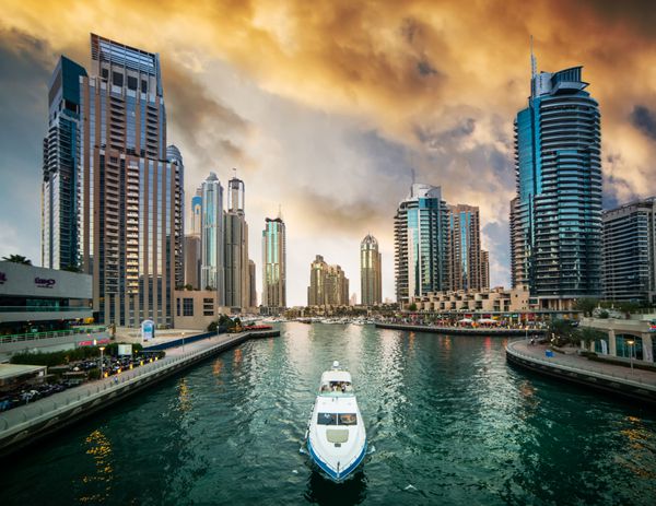 دبی امارات متحده عربی - 14 دسامبر 2013 آسمان خراش های مدرن و کانال آب با قایق های دبی مارینا در غروب آفتاب امارات متحده عربی