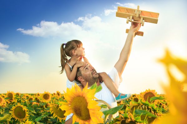 سرگرمی پدر و دختر در مزرعه آفتابگردان با هواپیمای چوبی