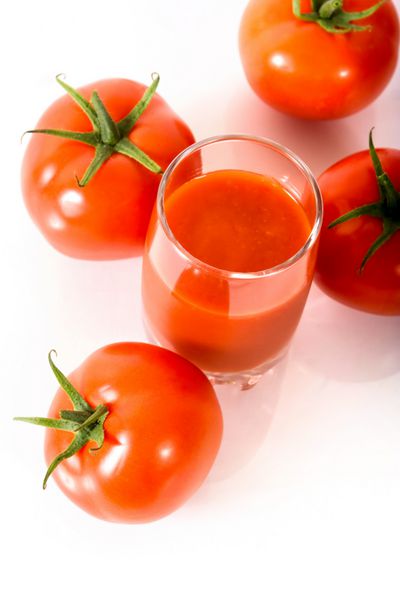 آب گوجه فرنگی در یک لیوان و گوجه فرنگی