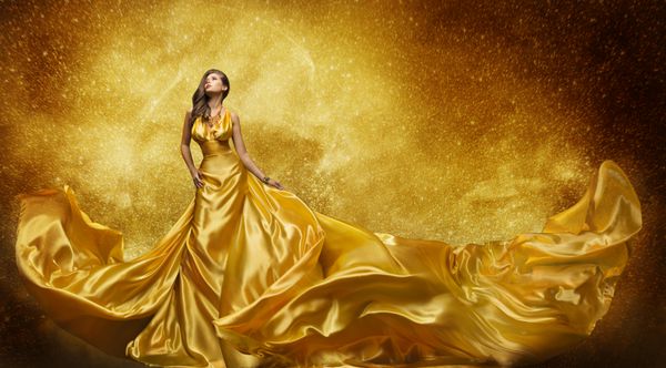 مدل لباس مد طلایی زنی با لباس پارچه ابریشمی طلایی دختر زیبا روی ستاره های آسمان که به بالا نگاه می کند