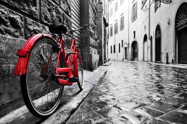دوچرخه قرمز قدیمی قدیمی در خیابان سنگفرش در شهر قدیمی رنگ در سیاه و سفید مفهوم دوچرخه جذاب قدیمی