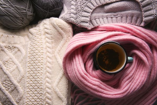 فنجان چای پیچیده شده در روسری و لباس گرم در کنار آن نزدیک