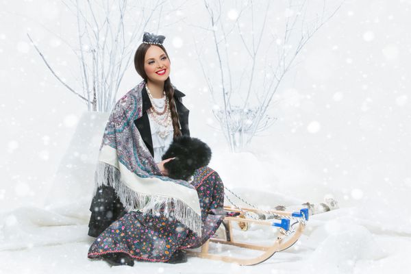 زن جوان زیبا با شال سنتی ملی روسی که توس را در آغوش گرفته است بارش برف کپی sp