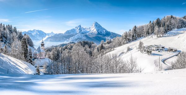 نمای پانوراما از چشم انداز زیبای زمستانی در کوه های آلپ باواریا با کلیسای زیارتی ماریا گرن و توده معروف واتزمن در پس زمینه پارک ملی berchtesgadener land باواریا آلمان