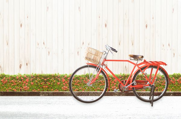 دوچرخه قرمز رنگ وینتیج با زمینه چوب سفید