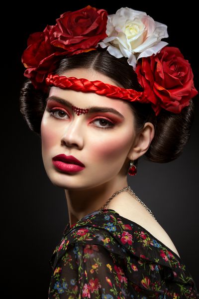 پرتره زن جوان زیبا با آرایش قرمز روشن و رز روی سر روی پس زمینه سیاه