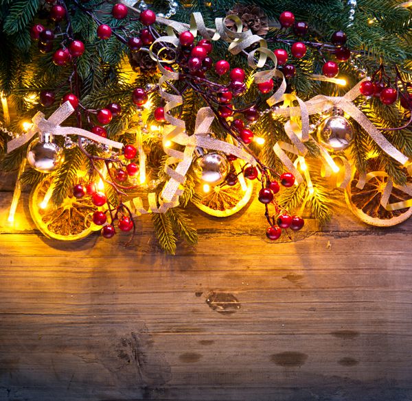 پس زمینه کریسمس درخت کریسمس با تزئین روی میز چوبی تیره طراحی هنر مرزی با درخت کریسمس گلدسته‌ها و گلدسته‌های روشن