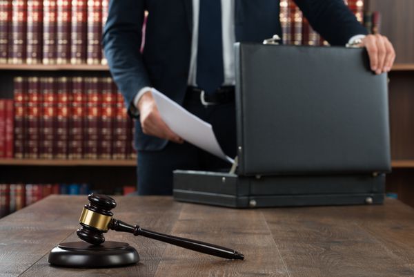 وسط وکیلی که مدارک را در کیف با چوب دستی روی میز دادگاه قرار می دهد