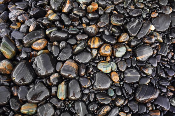 سنگ های دریا یا سنگ سیاه صاف مرطوب سنگریزه های سیاه در ساحل به عنوان پس زمینه پارک ملی تاروتائو تایلند