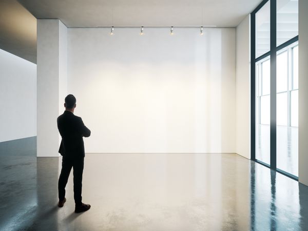 تاجر در فضای داخلی موزه سفید خالی با کف بتنی ایستاده است افقی