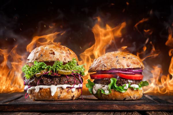 نمای نزدیک از همبرگرهای خانگی با شعله های آتش