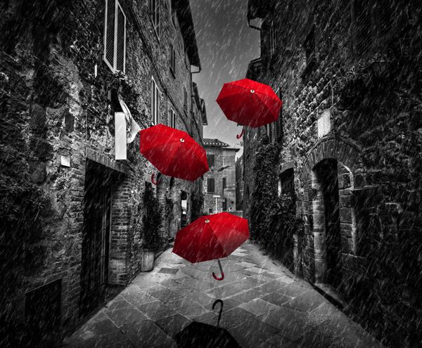 پرواز چتر با باد و باران در خیابان باریک تاریک در یک شهر قدیمی ایتالیایی در توسکانی ایتالیا سیاه و سفید با قرمز