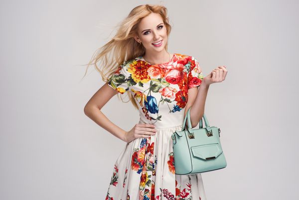 زن جوان زیبا با لباس بهاری زیبا کیف دستی در یک استودیو مد بهار تابستان po
