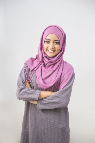 زن جوان مسلمان آسیایی با روسری لبخندی با دستان ضربدری