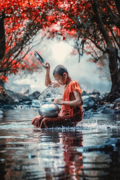 راهب کوچک در حال حمام کردن در آبشار نونگ کای تایلند