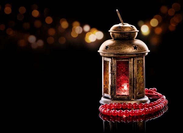 فانوس قدیمی با تسبیح قرمز حال و هوای ماه رمضان در شب با دکوراسیون سبک در پس زمینه