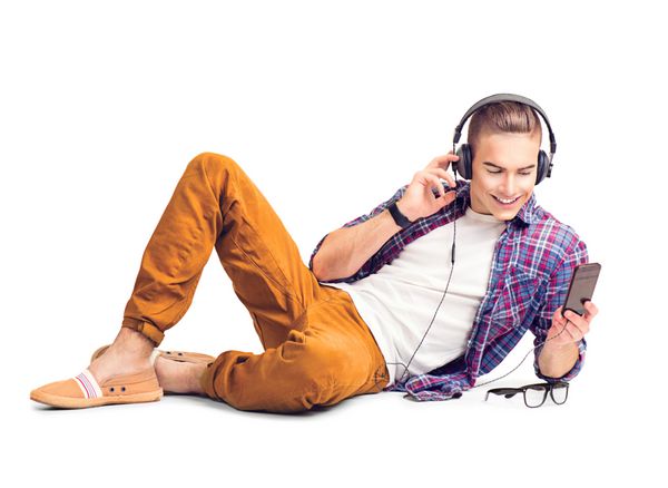 مرد جوان خوش تیپ هیپستر روی زمین دراز کشیده و با تلفن هوشمند به موسیقی گوش می دهد مرد جوان خوش‌تیپ با هدفون با گوشی هوشمند جدا شده در پس‌زمینه سفید