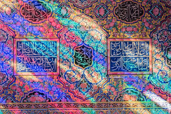 شیراز ایران - 17 اکتبر 2015 جزئیات دیوار توسط محراب در نصیرالملک یا مسجد صورتی در شیراز ایران با کاشی‌های پر از نور رنگارنگ که از پنجره‌های شیشه‌ای رنگارنگ می‌آید