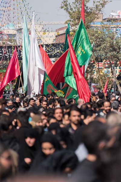 مشهد ایران - 24 اکتبر 2015 شیعیان با پرچم و لباس سیاه در عزاداری شهادت حسین بن علی در ماه محرم در شهر مشهد رژه می روند