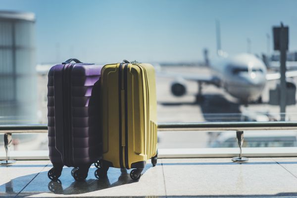 چمدان ها در سالن خروج فرودگاه هواپیما در پس زمینه مفهوم تعطیلات تابستانی چمدان های مسافر در محوطه انتظار ترمینال فرودگاه فضای داخلی سالن خالی با پنجره های بزرگ تمرکز بر روی چمدان ها