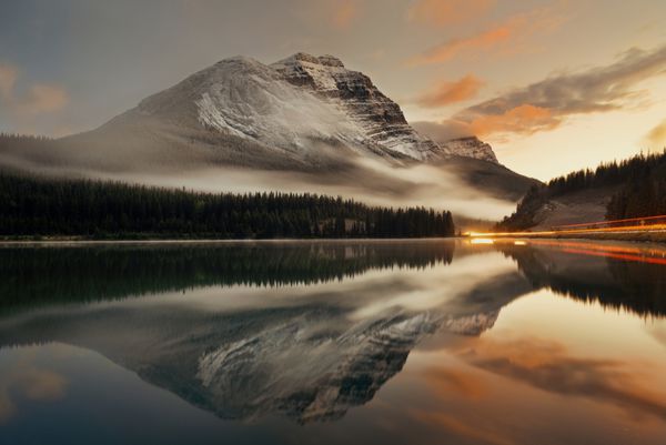 دریاچه کوه و مسیر چراغ راهنمایی با انعکاس و مه در غروب آفتاب در پارک ملی بنف کانادا
