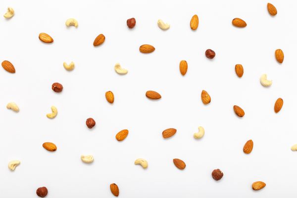 ترکیب الگوی آجیل تخمگذار تخت - فندق بادام هندی بادام را در زمینه سفید مخلوط کنید مفاهیمی در مورد دکوراسیون تغذیه سالم و پس زمینه غذا