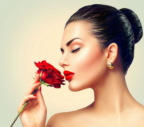 زن زیبایی با گل رز قرمز مدل مد دختر پرتره با گل رز قرمز در دست لب و ناخن قرمز آرایش و مانیکور لاکچری زیبا سبک مد