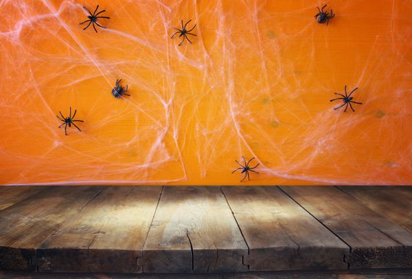 مفهوم تعطیلات هالووین میز خالی روستایی در مقابل پس زمینه تار عنکبوت آماده برای مونتاژ نمایش محصول